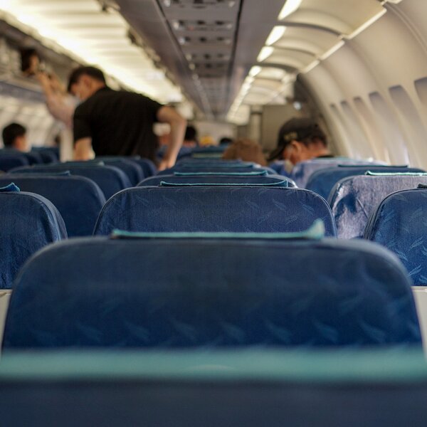 Intérieur d'un avion avec sièges bleus et passagers debout et assis