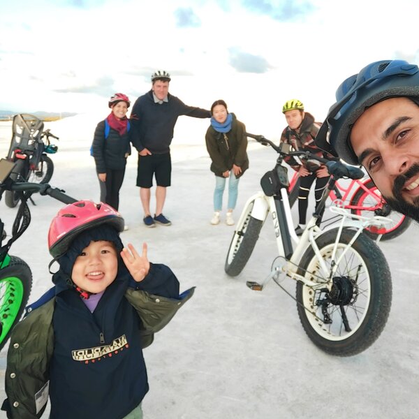 Group of people wearing helmets near electric bikes outdoors.