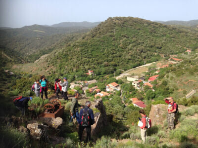 Groupe de randonneurs sur une colline verte surplombant un village.