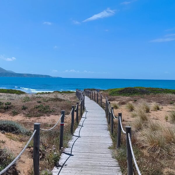 Passerelle en bois menant à la plage avec mer et ciel bleu