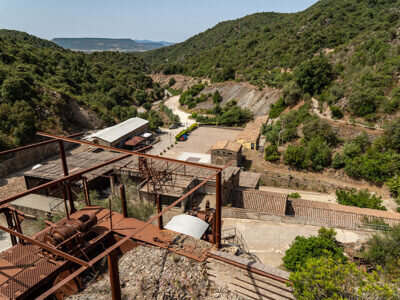Vue panoramique d'un site industriel abandonné parmi des collines verdoyantes.