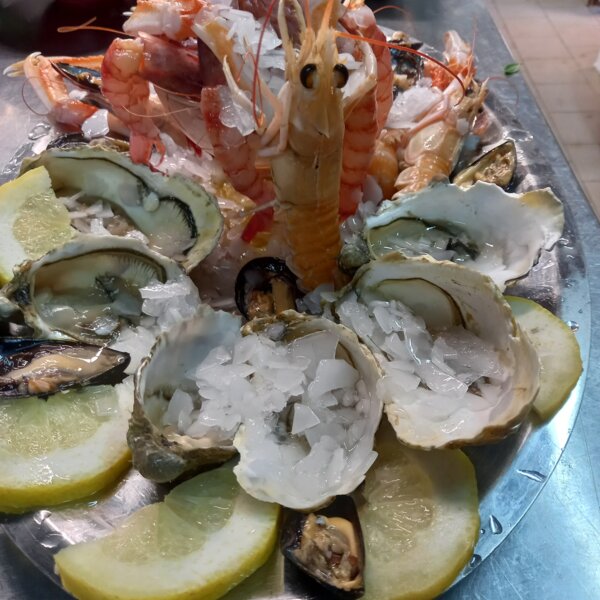 Plateau de fruits de mer avec huîtres, crevettes et tranches de citron sur glace.
