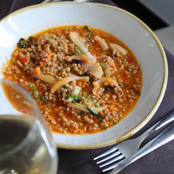 Bol de soupe de céréales avec calamars et légumes dans un bouillon rouge.