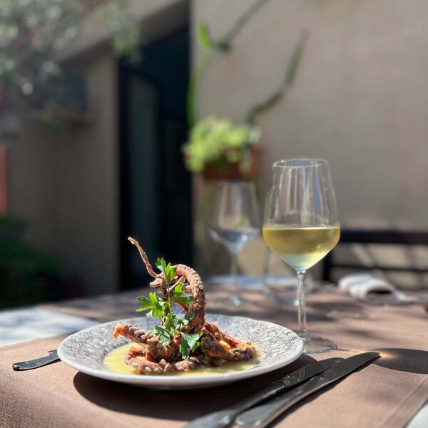 Plat de poulpe avec verre de vin blanc sur table extérieure