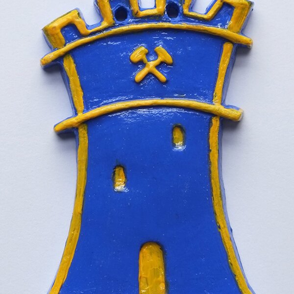 Blue tower sculpture with yellow details and crossed hammers symbol