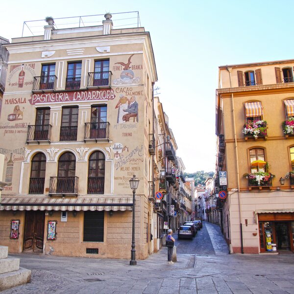 Historic building with advertising murals and cobblestone street in Italian city.